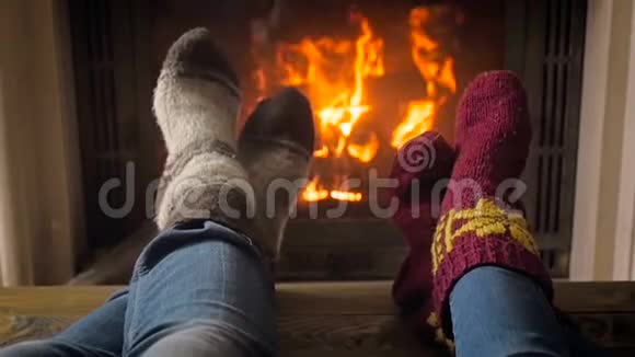 一对夫妇穿着针织毛袜在壁炉旁放松的特写慢镜头视频的预览图