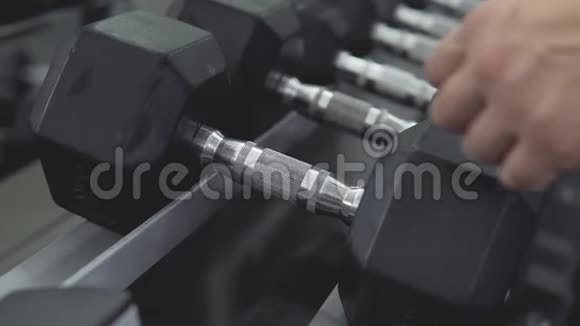 男子手提哑铃特写健身房力量训练器材视频的预览图
