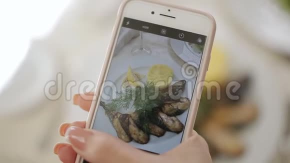 一个女人在一家餐馆里用手机相机为社交网络拍照食物视频的预览图