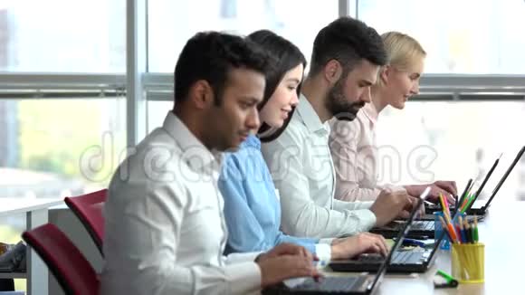 四名办公室职员坐在笔记本电脑上工作视频的预览图