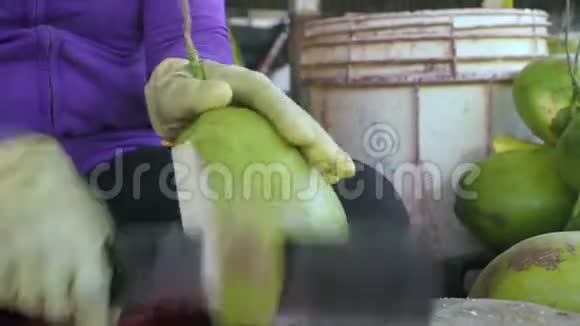 女性用刀将成熟的椰子剥开女人剥鲜椰子喝果汁视频的预览图