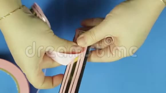 一个女人用粉色丝带做礼物蝴蝶结图案蓝色背景视频的预览图