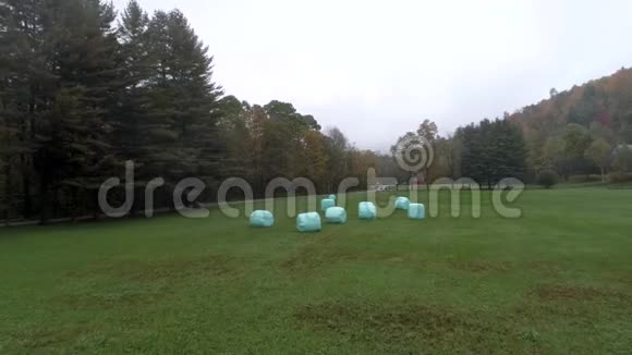 空中钻孔机在佛蒙特州秋季用塑料包裹的干草飞越野外视频的预览图