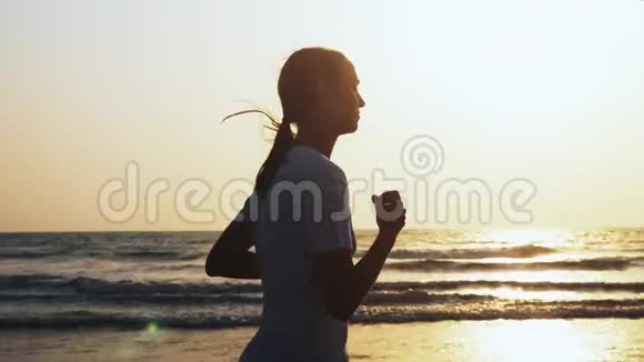 适合运动的女人正在日落时在海滩上慢跑视频的预览图