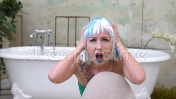 一个年轻女子在浴室里用手捂着头惊恐地尖叫视频的预览图