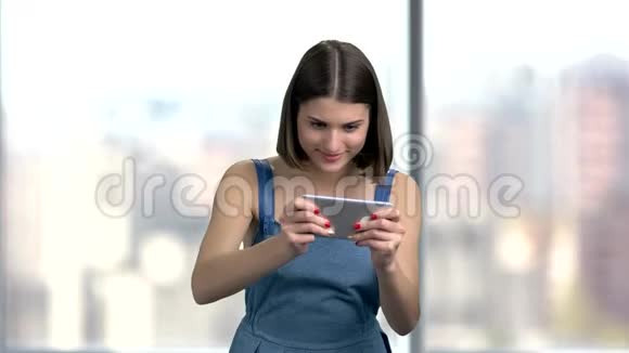 快乐的情感女人在智能手机上玩视频的预览图