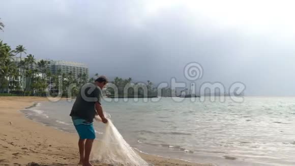 渔夫在海滩上拿着渔网视频的预览图