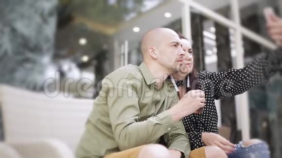 男人和女人在街头咖啡馆喝茶在智能手机上自拍视频的预览图