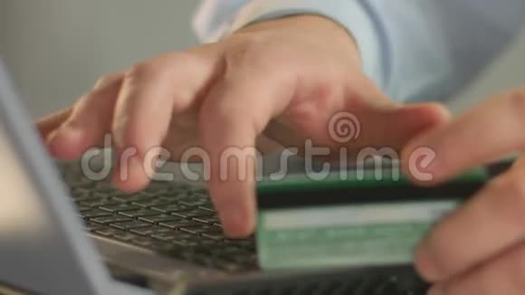 商人在笔记本电脑上输入银行卡号用手指特写视频的预览图