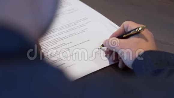 后视一名商人穿黑色衬衫签订合同库存把他的签名放在重要文件上视频的预览图