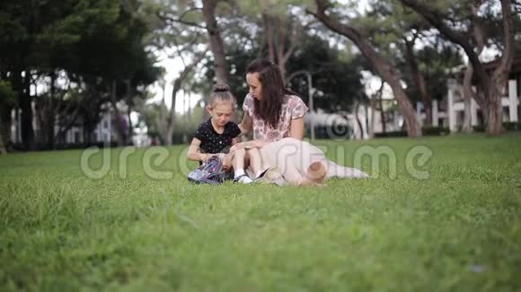 妈妈带着一个哭泣的女儿坐在草地上妈妈安慰女儿视频的预览图