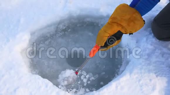 渔人之手为冬季捕鱼从冰中清理潜洞视频的预览图