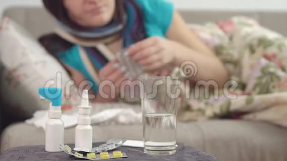 椅子上的药片喷雾剂和水年轻的生病的女人在床上服用一片药丸视频的预览图