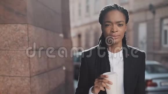 一幅严肃的非洲裔美国商人的肖像穿着西装在城市里走来走去喝着咖啡她看上去视频的预览图