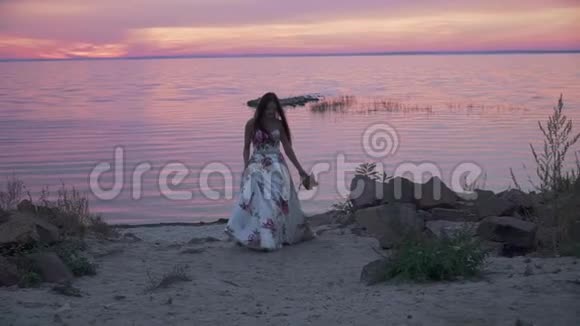 可爱的女孩穿着长裙子沿着河岸散步视频的预览图