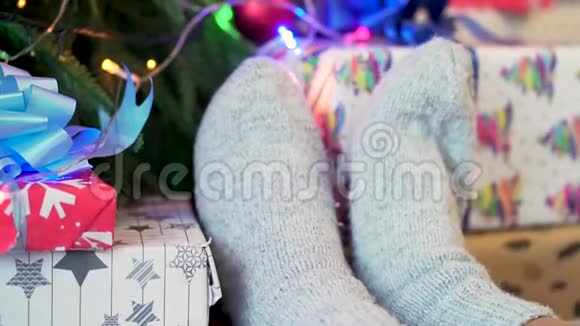 白色针织袜子在女性脚上装饰圣诞树背景节日及新年概念视频的预览图