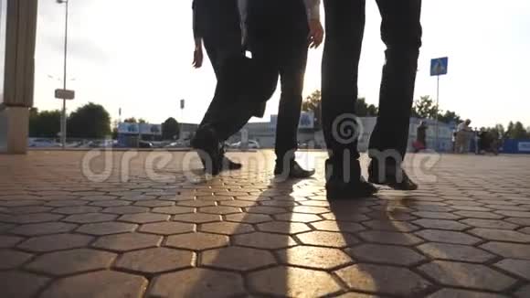 三个商人的脚在机场附近行走背景是太阳耀斑商人们一起去码头视频的预览图