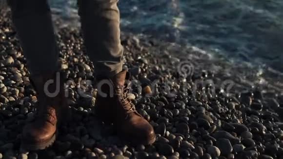 近景拍摄的是那些穿着靴子的人的脚他们的脚靠近海边的一块石头视频的预览图