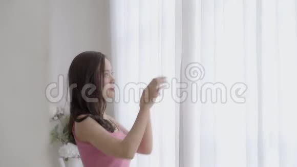 美丽的肖像年轻的亚洲女人在卧室里打开窗帘望着外面的希望和未来视频的预览图