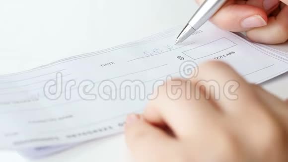 女商人用钢笔填写一千美元银行支票的特写镜头视频的预览图