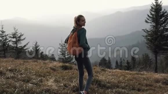 幸福的女人徒步旅行者在夕阳的映衬下走在山脊的边缘视频的预览图