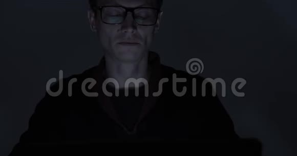 深夜在黑暗房间里用笔记本电脑工作的男人的肖像视频的预览图