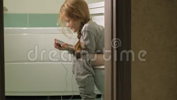 小女孩坐在马桶上用电话视频的预览图