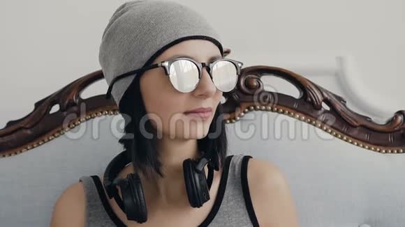 美丽的年轻女孩戴着耳机和太阳镜在室内侧视和微笑的肖像关于视频的预览图