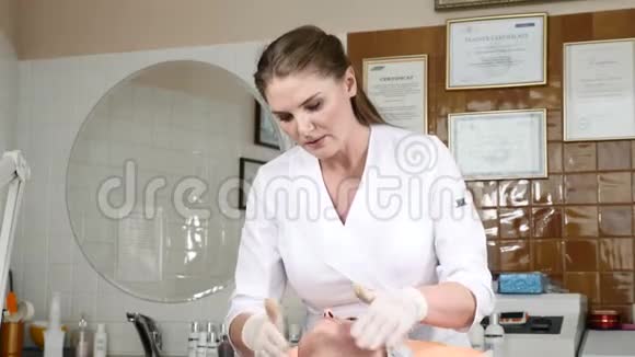手套美容师在敷美容面膜前对年轻女性面部进行按摩年轻漂亮的女客户视频的预览图