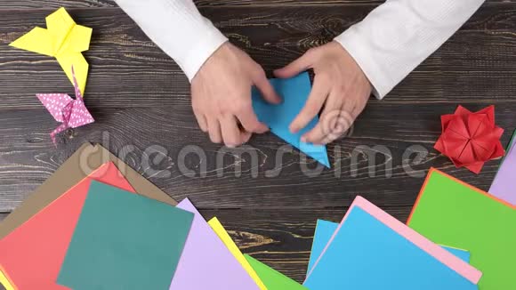 男手用蓝纸创作折纸俯视图视频的预览图