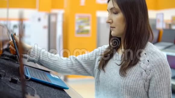一个家电店里的年轻女人挑选笔记本电脑视频的预览图