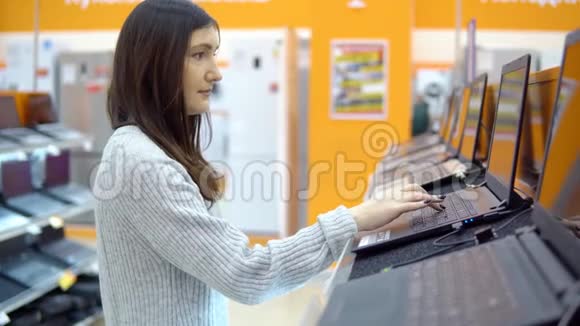 年轻的黑发女人在五金店里挑选笔记本电脑视频的预览图