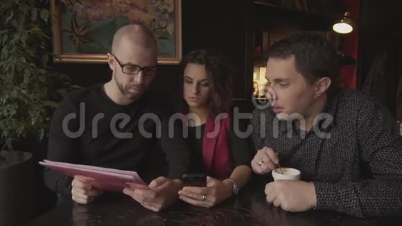 一家咖啡店里的两个男人和女人谈论他们的商业计划视频的预览图