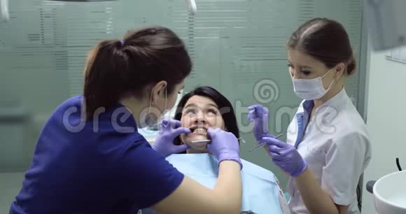牙科护士坐在病人旁边牙科医生用镜子开始治疗病人视频的预览图