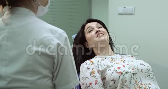病人坐在牙医椅上护士为她准备检查病人张开嘴牙医视频的预览图