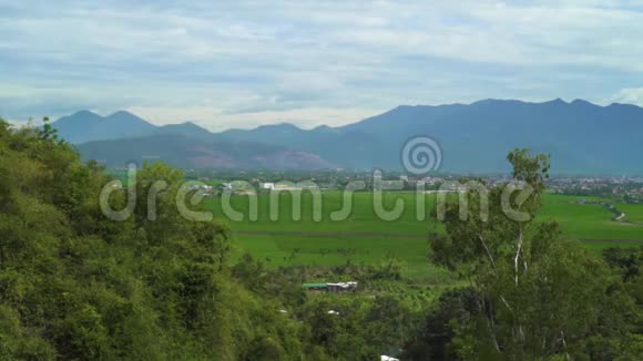 农业稻田和群山在蓝天背景上剪影绿地田野和山岭景观视频的预览图