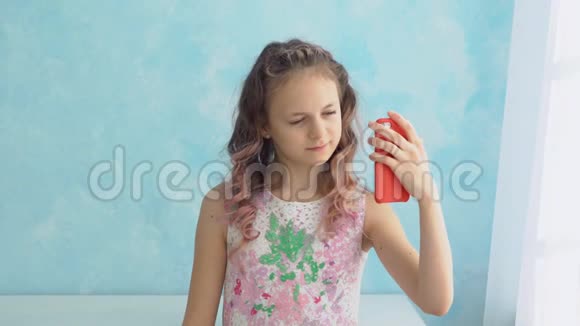 女孩正在蓝墙背景下打电话拍照视频的预览图