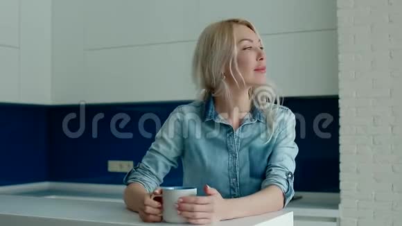 年轻的白人妇女在现代化的厨房里喝咖啡视频的预览图