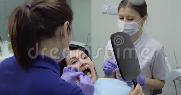 牙医正在用镜子检查牙齿护士坐在旁边视频的预览图
