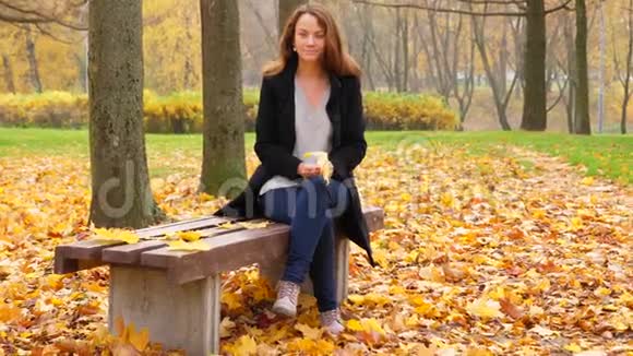 坐在公园里的女人手里拿着黄色的枫叶视频的预览图