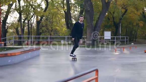 极限滑板者听音乐耳机磨下栏杆在滑板公园慢镜头视频的预览图