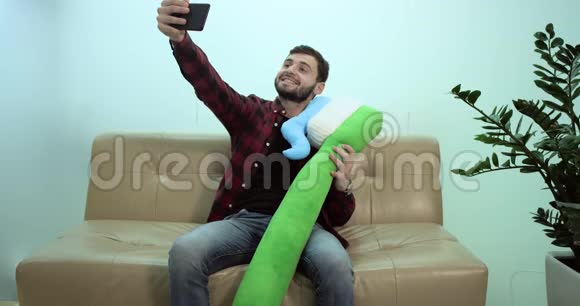 微笑的男人坐在沙发上用刷牙自拍视频的预览图