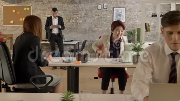 在办公室工作的混合种族的商人和突然开始欢呼和跳舞的亚洲女人每个人视频的预览图