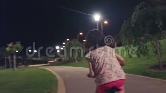 小女孩晚上在公园里骑自行车视频的预览图