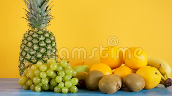 黄色背景下的橘子香蕉菠萝猕猴桃和葡萄视频的预览图