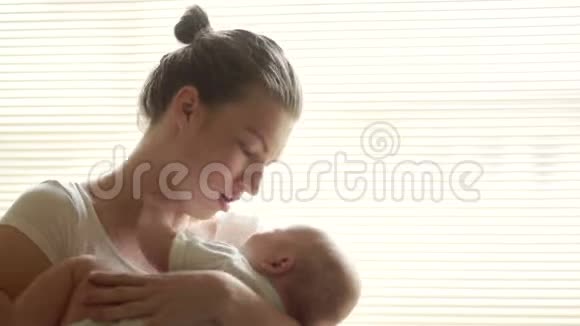 母亲抱着她的孩子她给他唱摇篮曲妈妈和宝宝穿着白色的衣服母亲节视频的预览图