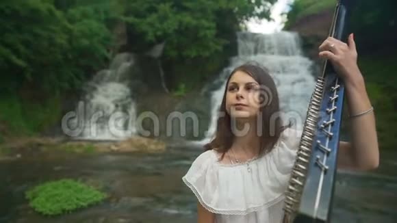 女性的手轻轻地触到瀑布处的琴弦视频的预览图