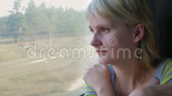 一位年轻女子坐火车旅行望着窗外的风景视频的预览图