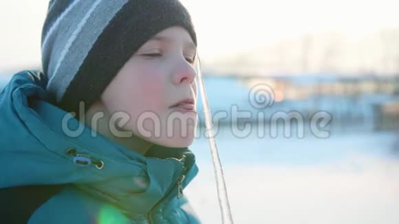 一个男孩舔冰棍下雪的霜天晴天新鲜空气中的乐趣和游戏视频的预览图
