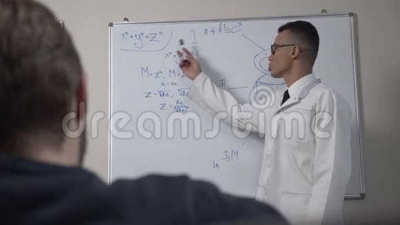 一位年轻成功的非洲科学家身穿白色外套和眼镜站在黑板前拿着公式和演示文稿视频的预览图